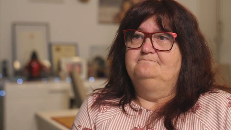 Heike Frohnhöfer, eine Frau mit dunkelroten Haaren und Brille, blickt traurig von der rechten in die linke Bildhälfte
