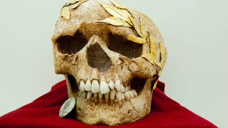 Römischer Totenschädel mit einer Münze im Mund – ein Obolus für Charon, den Fährmann der Toten in der griechischen Mythologie